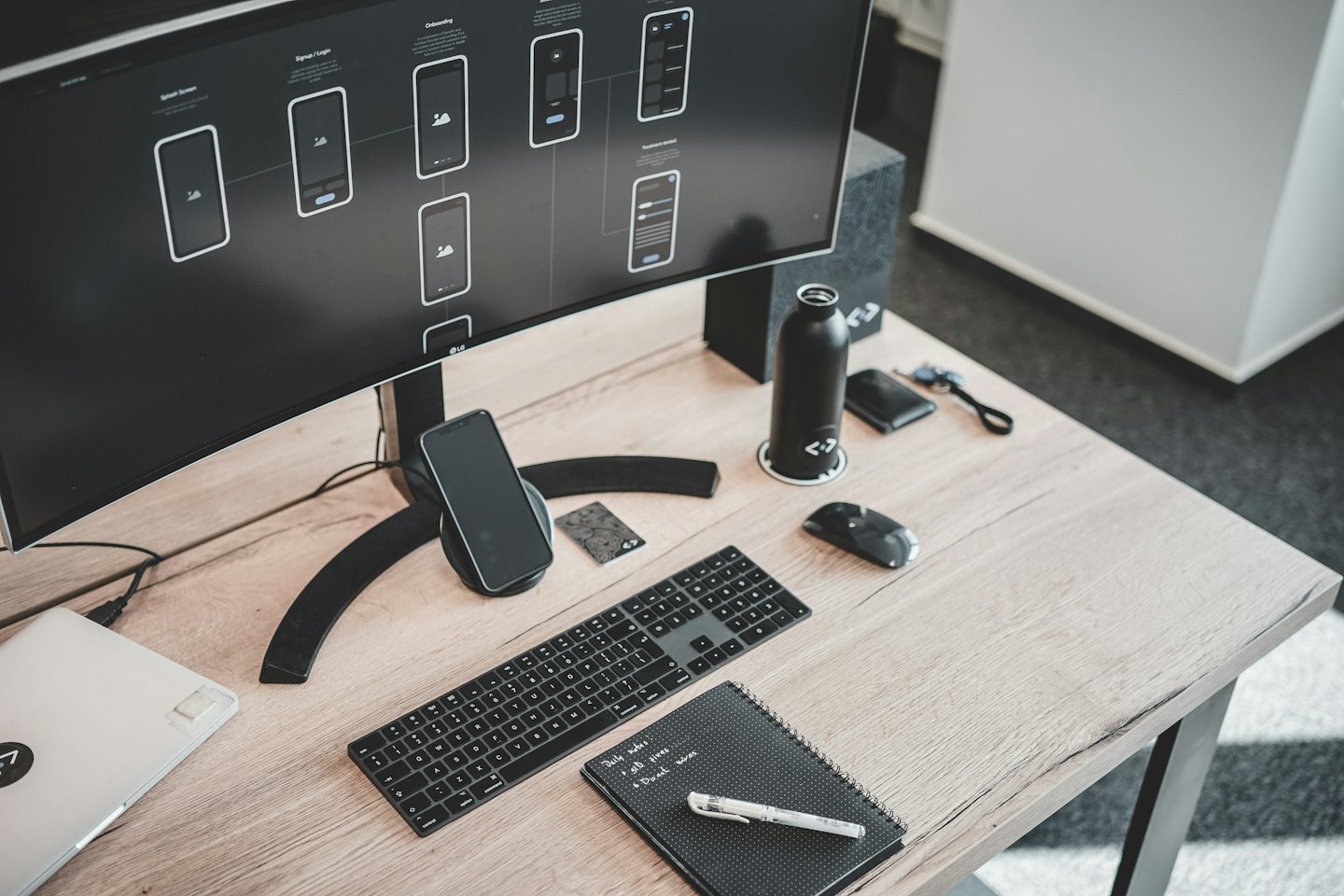 Meja desainer modern dengan monitor menampilkan kerangka aplikasi.