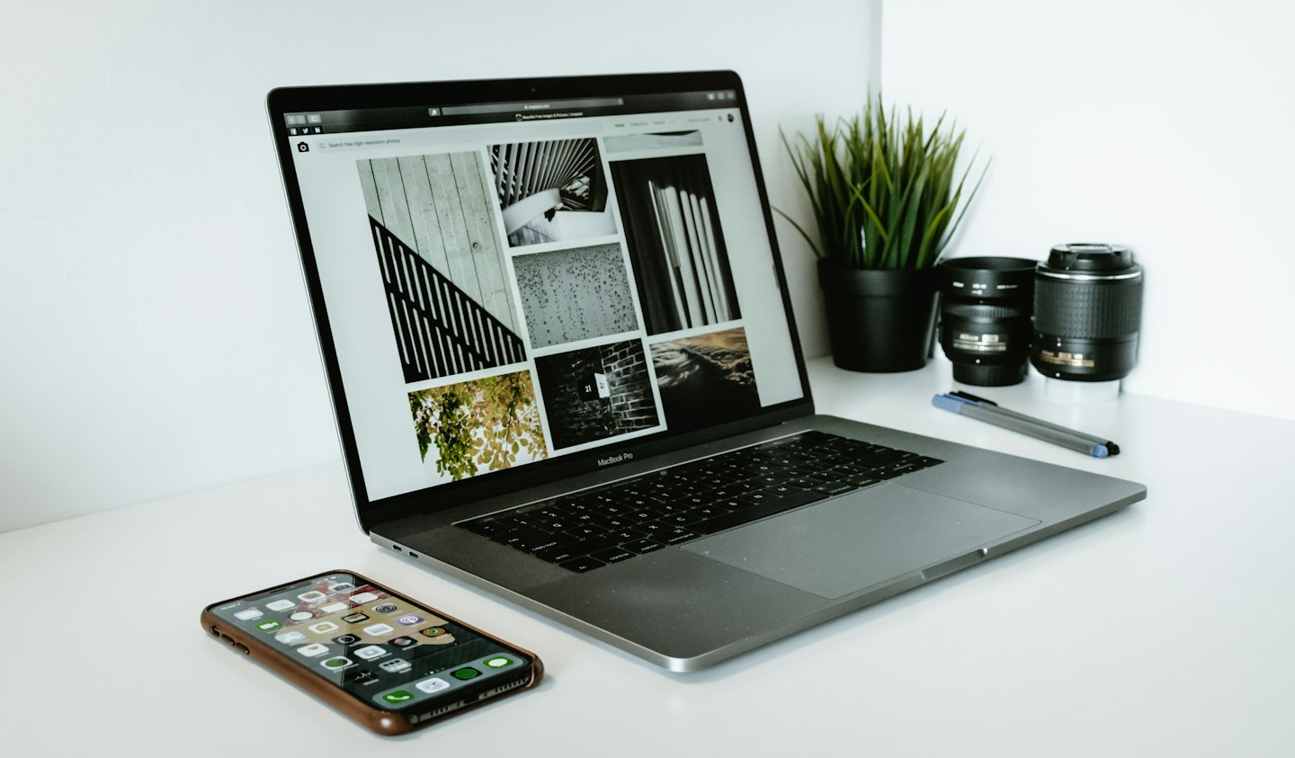 Laptop di meja putih menampilkan situs web galeri foto.
